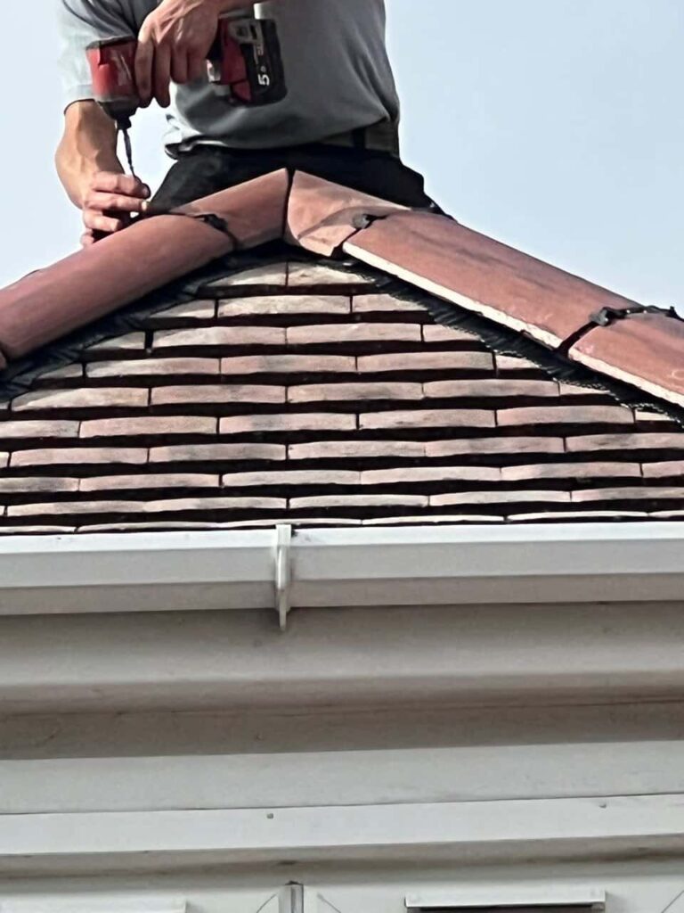 This is a photo of one of the operatives of MCM Roofing Repairs Warminster installing new ridge tiles