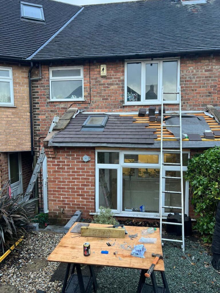 This is a photo of a roof extension that is having new roof tiles installed. This is a photo taken from the roof ridge looking down a tiled pitched roof on to a flat roof. Works carried out by MCM Roofing Repairs Warminster